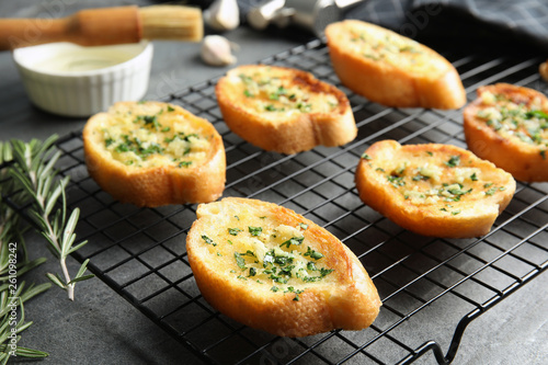 Baking rack with tasty homemade garlic bread on table