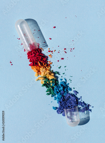 Pill that makes you feel better in opened capsule form with rainbow colored powder spilling out photo