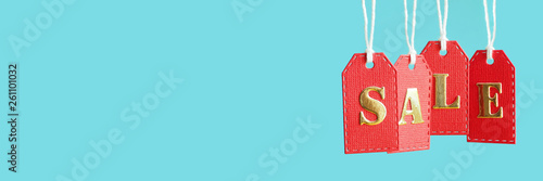 inscription sale in gold letters on red hanging labels on a blue background  in popular social media banner proportions. copy space...