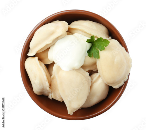 Tasty dumplings with sour cream and parsley in bowl isolated on white, top view