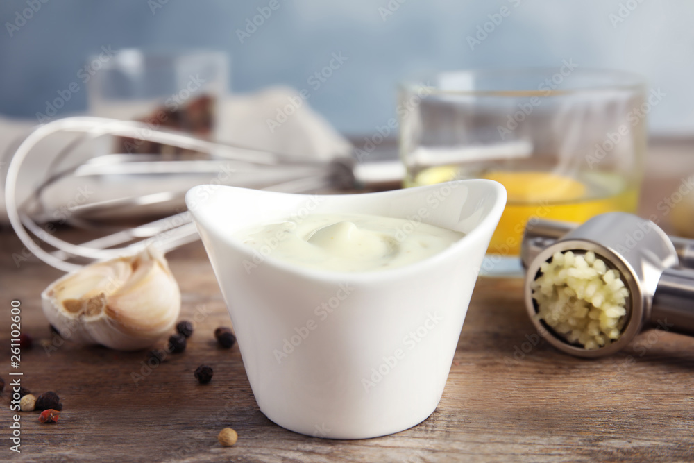 Composition with bowl of garlic sauce on wooden table Composition with bowl of garlic sauce on wooden table