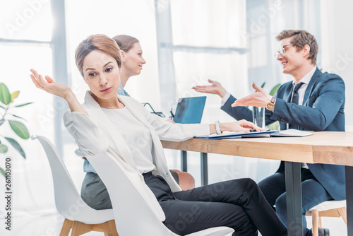 attractive emotional recruiter gesturing near man in glasses talking during job interview