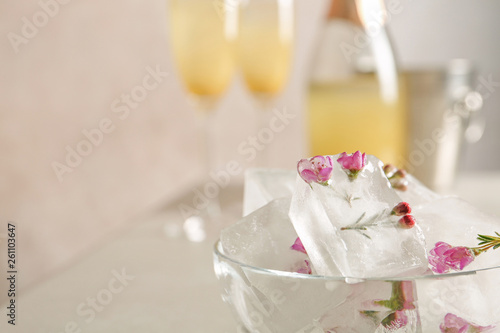 Bowl with floral ice cubes on table, closeup. Space for text