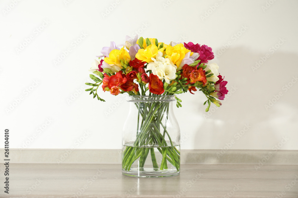 Beautiful bright freesia flowers in vase on table Beautiful bright freesia flowers in vase on table