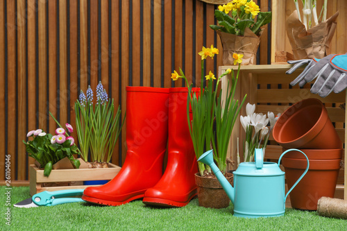 Composition with different gardening tools on artificial grass at wooden wall