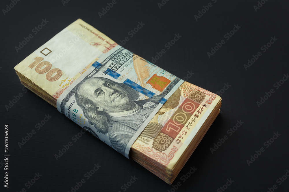 Value of Ukrainian hryvnia and American dollars. A pack of Ukrainian hryvnia wrapped one hundred dollar bill Value of Ukrainian hryvnia and American dollars. A pack of Ukrainian hryvnia wrapped one hundred dollar bill