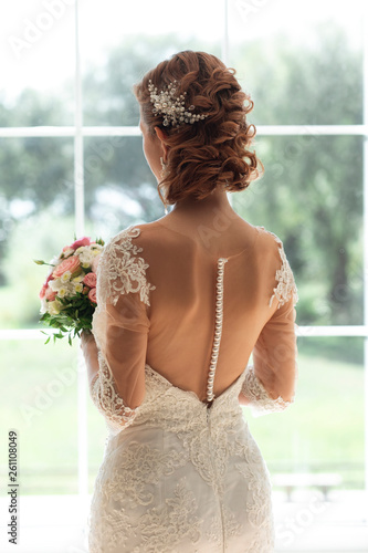 Bride with bouquet by window photo