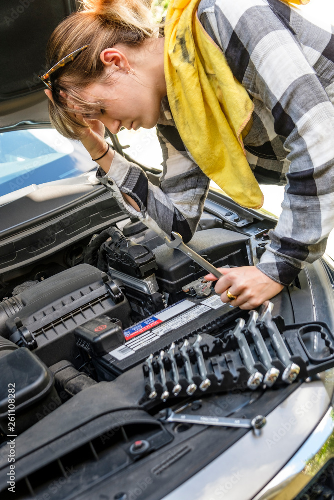 Frustrated woman repairing car Frustrated woman repairing car