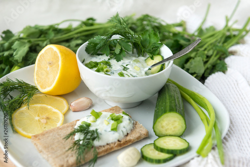 Greek yogurt with herbs in a plate, cucumber, garlic, lemon, dill, parsley,