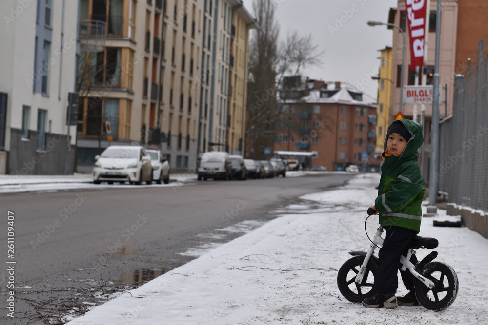 Kid boy biking in the snow