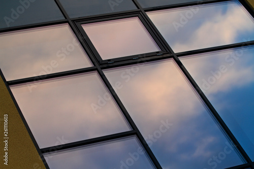 A window of an urban building. Sky and clouds are reflecting on the window