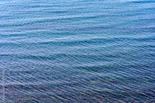 Sea ripples and clear water through which the seabed is visible with stones and algae