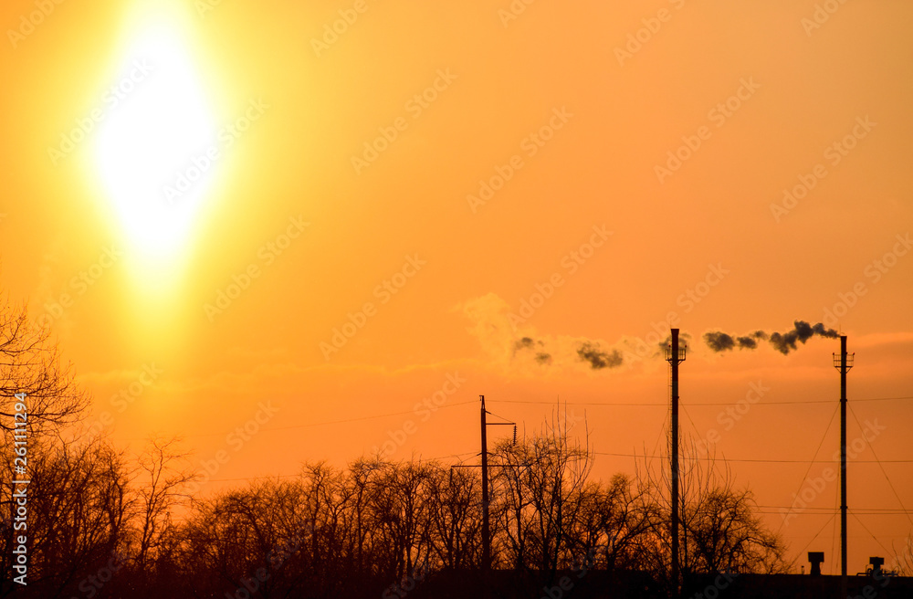 Smoke from the boiler pipes at sunset. Winter landscape