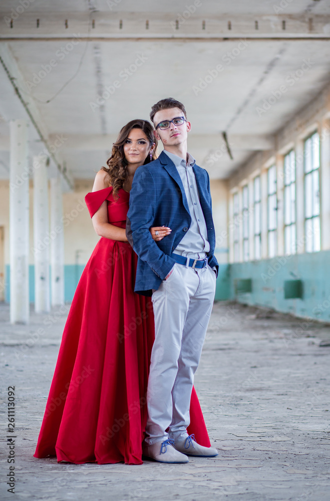 Prom couple. Handsome guy in blue suit and beautiful girl in glamorous red dress, ready for their prom night