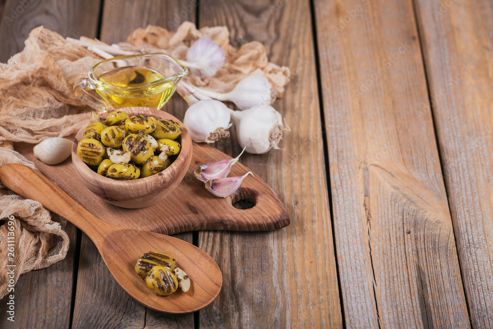 Fototapeta premium Grilled olives with garlic, olive oil and spices on rustic wooden table