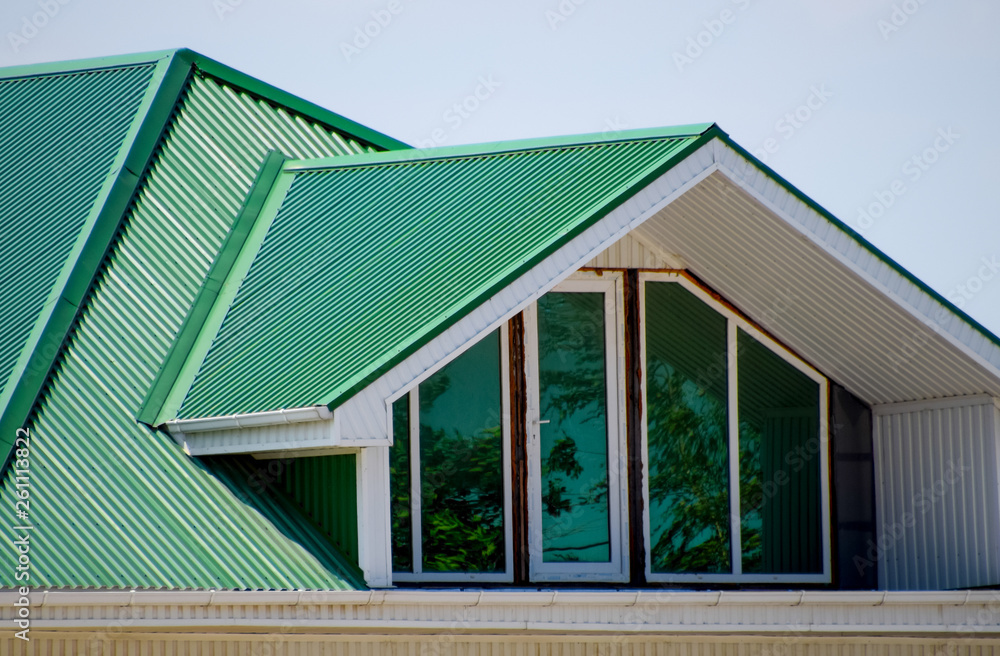 The house with plastic windows and a green roof of corrugated sheet. Green roof of corrugated metal profile and plastic windows. The house with plastic windows and a green roof of corrugated sheet. Green roof of corrugated metal profile and plastic windows.