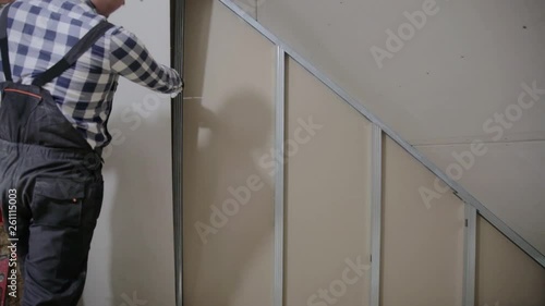 Man installing plasterboard sheet to wall for attic room construction