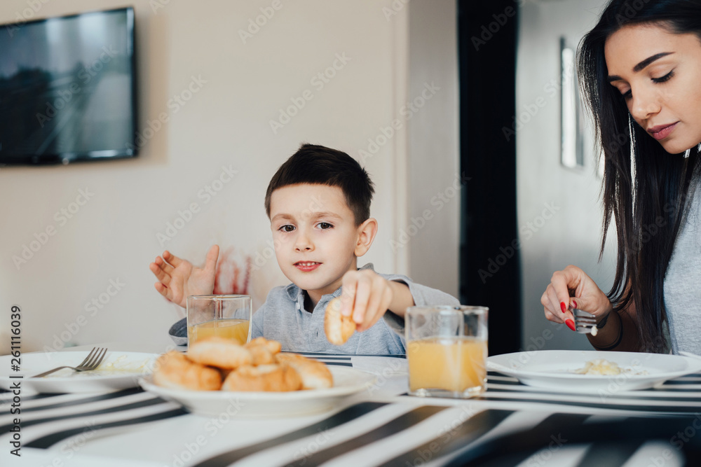 Beautiful young woman at home with her little cute son are having breakfast. Beautiful young woman at home with her little cute son are having breakfast.
