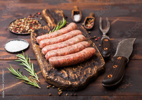 Photography Raw beef and pork sausage on old chopping board with vintage knife and fork on dark wooden background