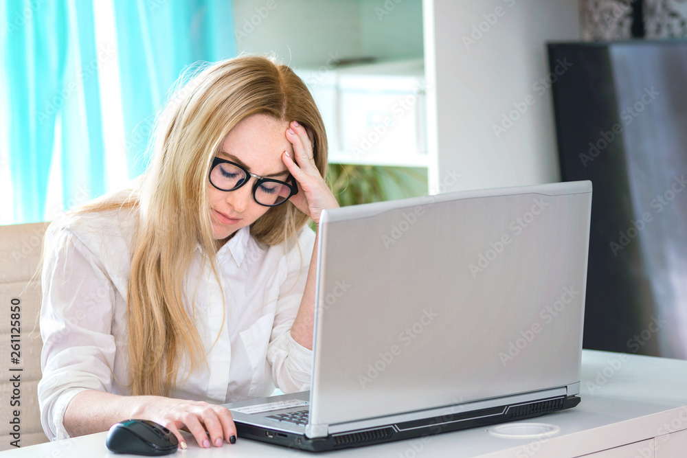 Tired overworked freelancer working with a laptop in an office or home. Young businesswoman with tired eyes and headache Tired overworked freelancer working with a laptop in an office or home. Young businesswoman with tired eyes and headache