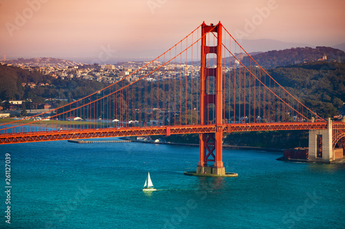 Yacht passing under Golden Gate Bridge at sunset