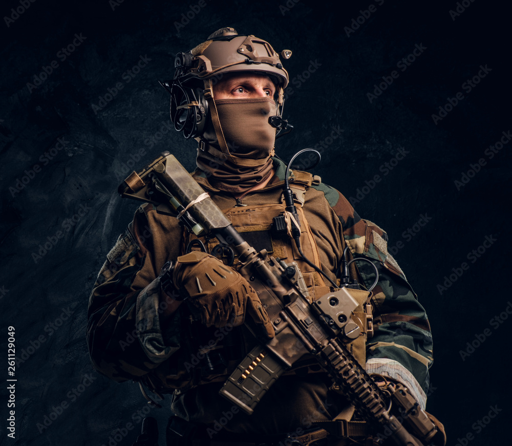 Elite unit, special forces soldier in camouflage uniform posing with assault rifle.