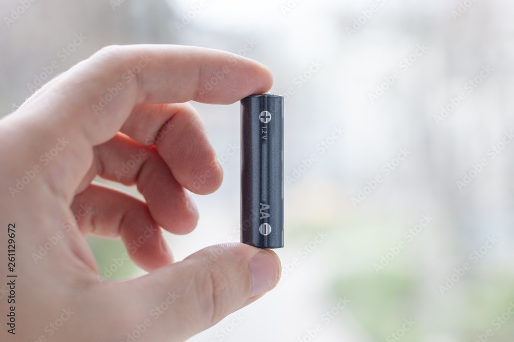 battery cell in hand at light abstract background. battery cell in hand at light abstract background.