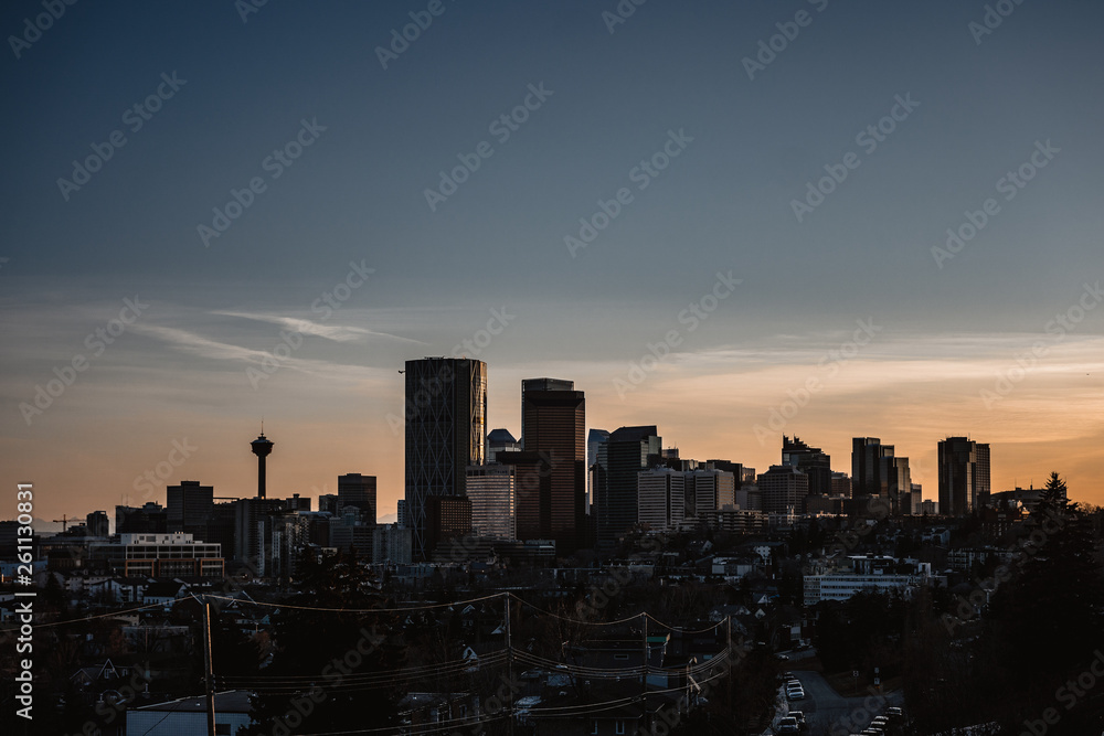 Calgary skyline in the early morning with rays from rising sun reflecting off glass buildings.