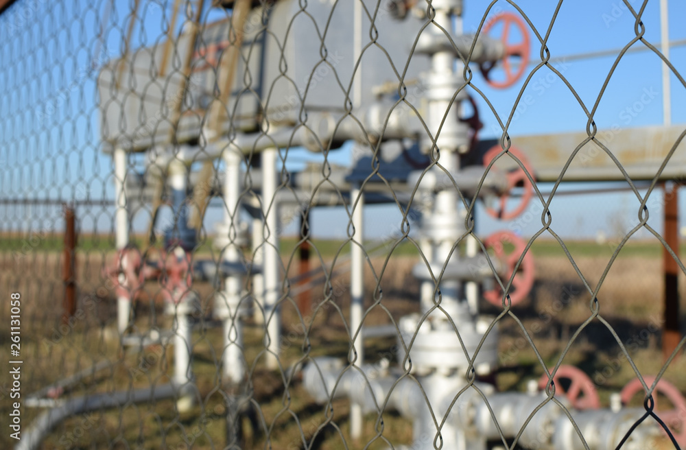 Grid the chain-link near an oil well.