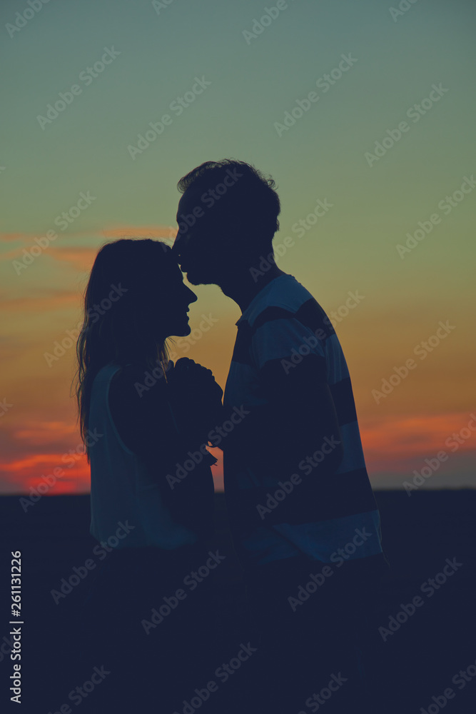 Silhouettes of a couple in sunset / sunrise time.