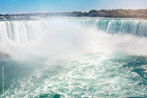 Aerial top landscape view of Niagara Falls between United States of America and Canada. Horseshoe of Canadian waterfall on sunny day. Water tour boat at famous tourist landmark