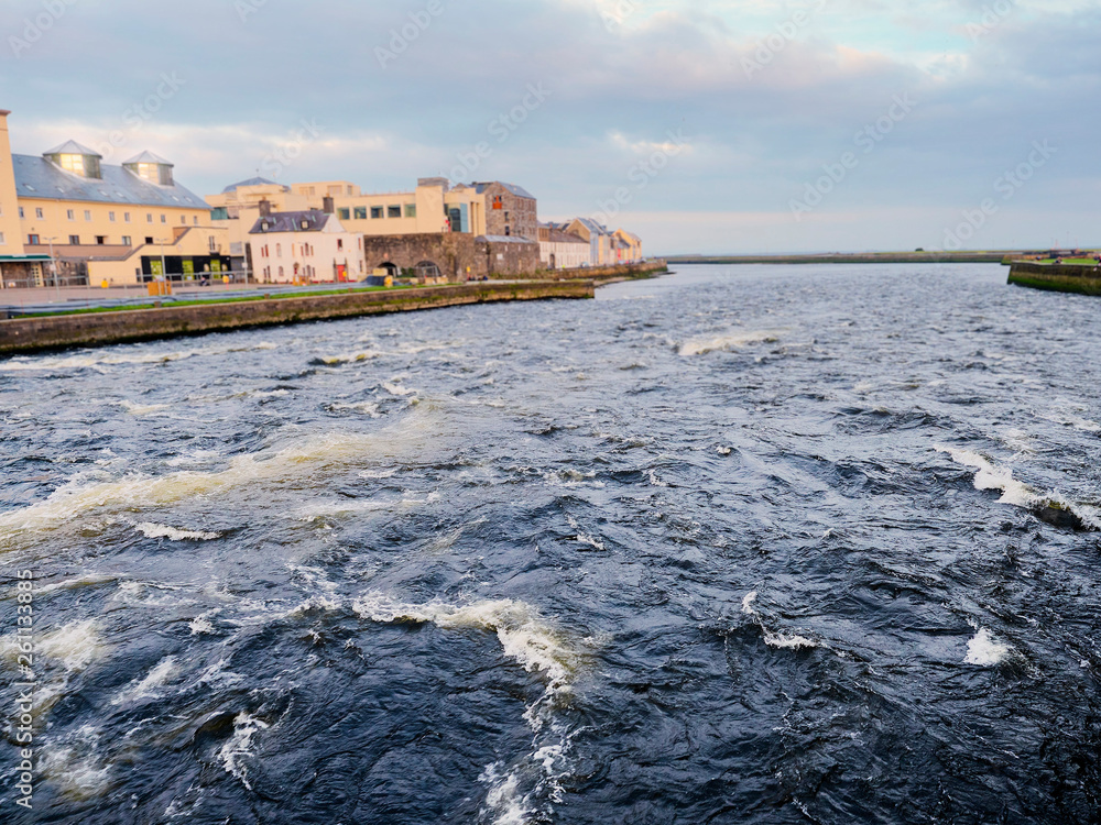 River Corrib and left bank of the river, Galwy city, Ireland. Water is high and powerful.
