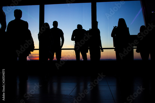 People standing and looking at a view, airport and travel business silhouettes with a sunset backgound