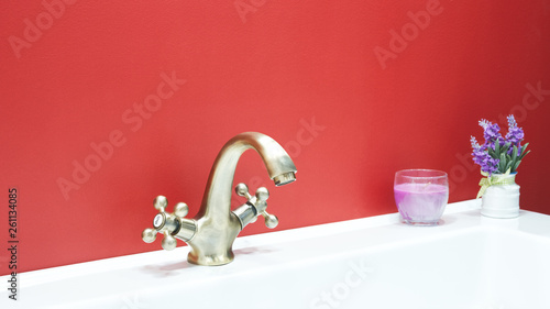 Luxury retro style bronze faucet mixer on a white sink in a beautiful red bathroom photo