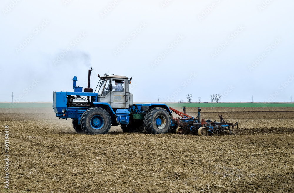 Lush and loosen the soil on the field before sowing. The tractor plows a field with a plow Lush and loosen the soil on the field before sowing. The tractor plows a field with a plow