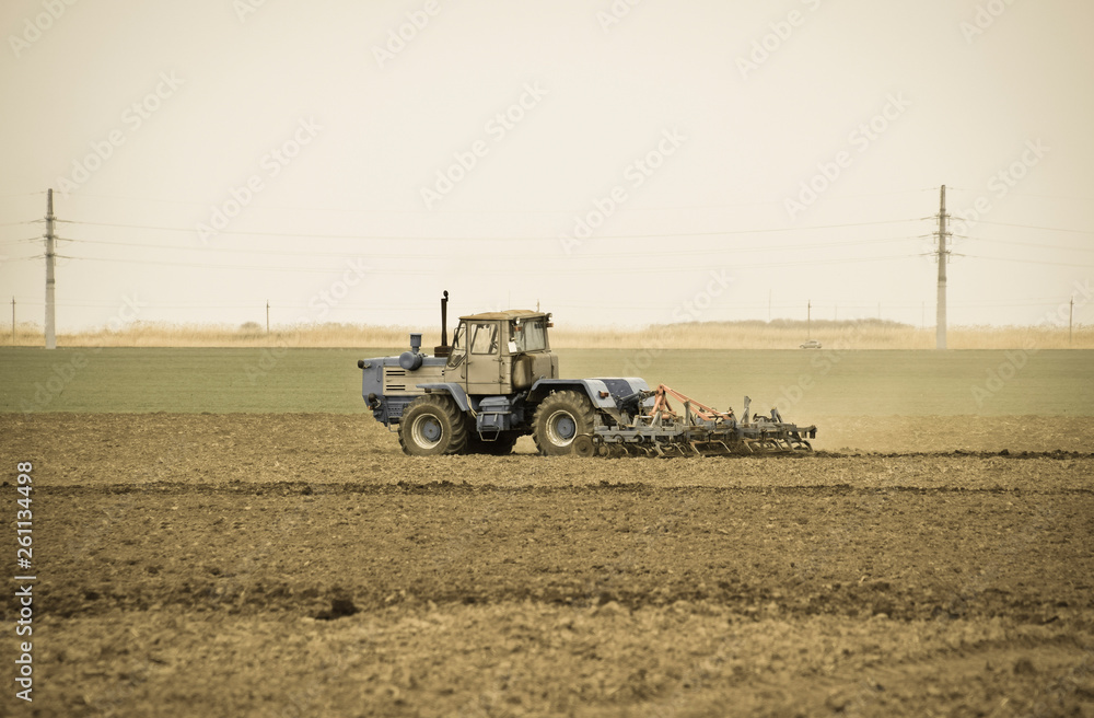 Lush and loosen the soil on the field before sowing. The tractor plows a field with a plow Lush and loosen the soil on the field before sowing. The tractor plows a field with a plow