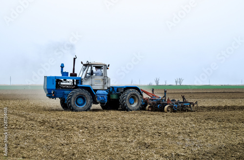 Lush and loosen the soil on the field before sowing. The tractor plows a field with a plow