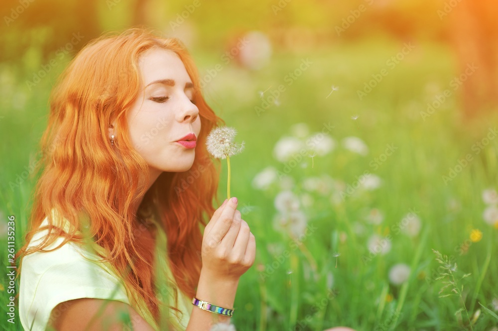 Portrait of young redhair woman blowing dandelion with joy in spring garden. Springtime Beautiful girl at sunset in meadow landscape. Allergic to pollen of flowers. Spring allergy free healthy concept Portrait of young redhair woman blowing dandelion with joy in spring garden. Springtime Beautiful girl at sunset in meadow landscape. Allergic to pollen of flowers. Spring allergy free healthy concept