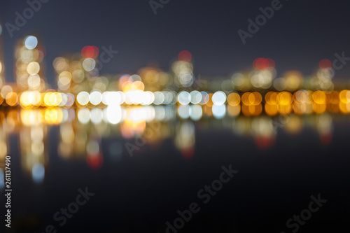 blurred dark cityscape with illuminated buildings, reflection and bokeh lights