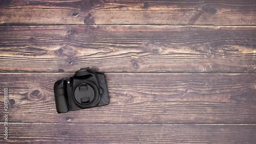 Travel kit camera tripod and battery on wooden background - Stop motion 