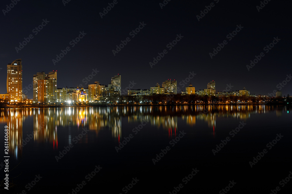 picturesque dark cityscape with illuminated buildings, river and night sky