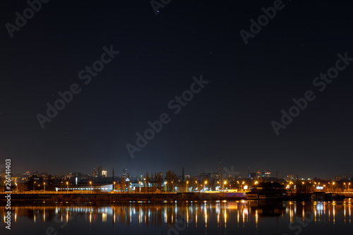 dark cityscape with buildings, lights and river at night
