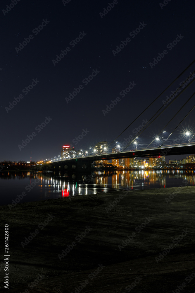 cityscape with illuminated buildings, bridge and river at nigth