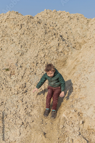A little boy is climbing a sand mountain.