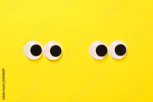Googly eyes of a quarreling pair of lovers on yellow background. Mad funny toys eyes close up.
