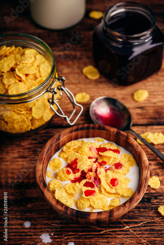 Breakfast with corn flakes, milk and berry syrup