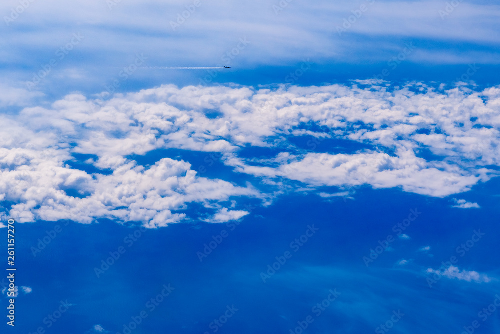 Plane of commercial flights crossing a sky of blue and white clouds seen from above, on the Mediterranean.