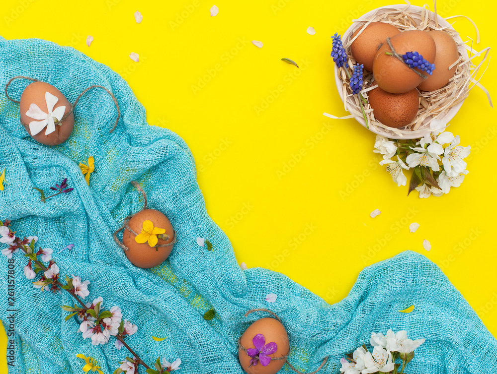 Top view on easter decor, painted eggs on bright yellow background with place for text and spring flowers. Bright preparation of Easter cards. Orthodox and Catholic holiday. family celebration