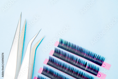 tools for Eyelash Extension Procedure. Two tweezers with artificial black lashes on blue background. copyspace mockup - Beauty and fashion concept