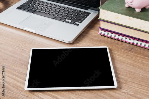 Blank screen digital tablet with office equipment on office desk.